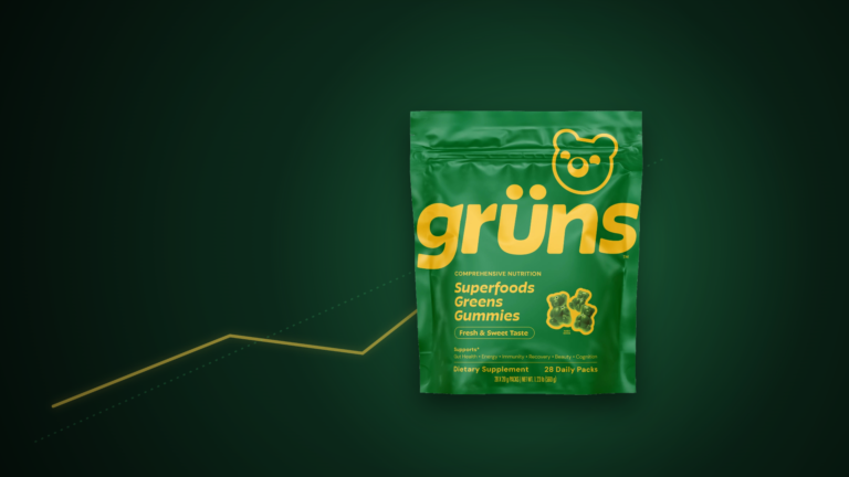 Grüns Superfoods Greens Gummies pouch on a dark editorial background with a rising green acquisition arrow, signaling Unilever’s $1.2B purchase