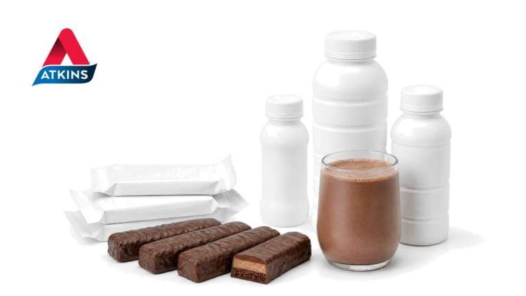 Plain white protein shake bottles, chocolate-coated protein bars and a glass of chocolate shake on white, with the Atkins logo