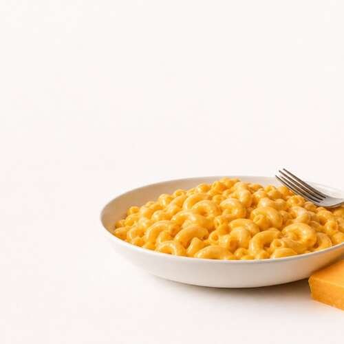Bowl of creamy macaroni and cheese with a fork and a wedge of cheddar, with the Bob Evans Farms logo