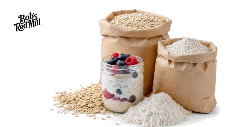 Kraft paper bags of flour and rolled oats with spilled oats and a jar of overnight oats on white, with the Bob's Red Mill logo