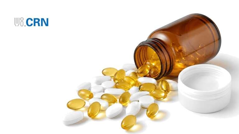 An amber supplement bottle on its side with softgels and tablets spilling out, with the CRN logo