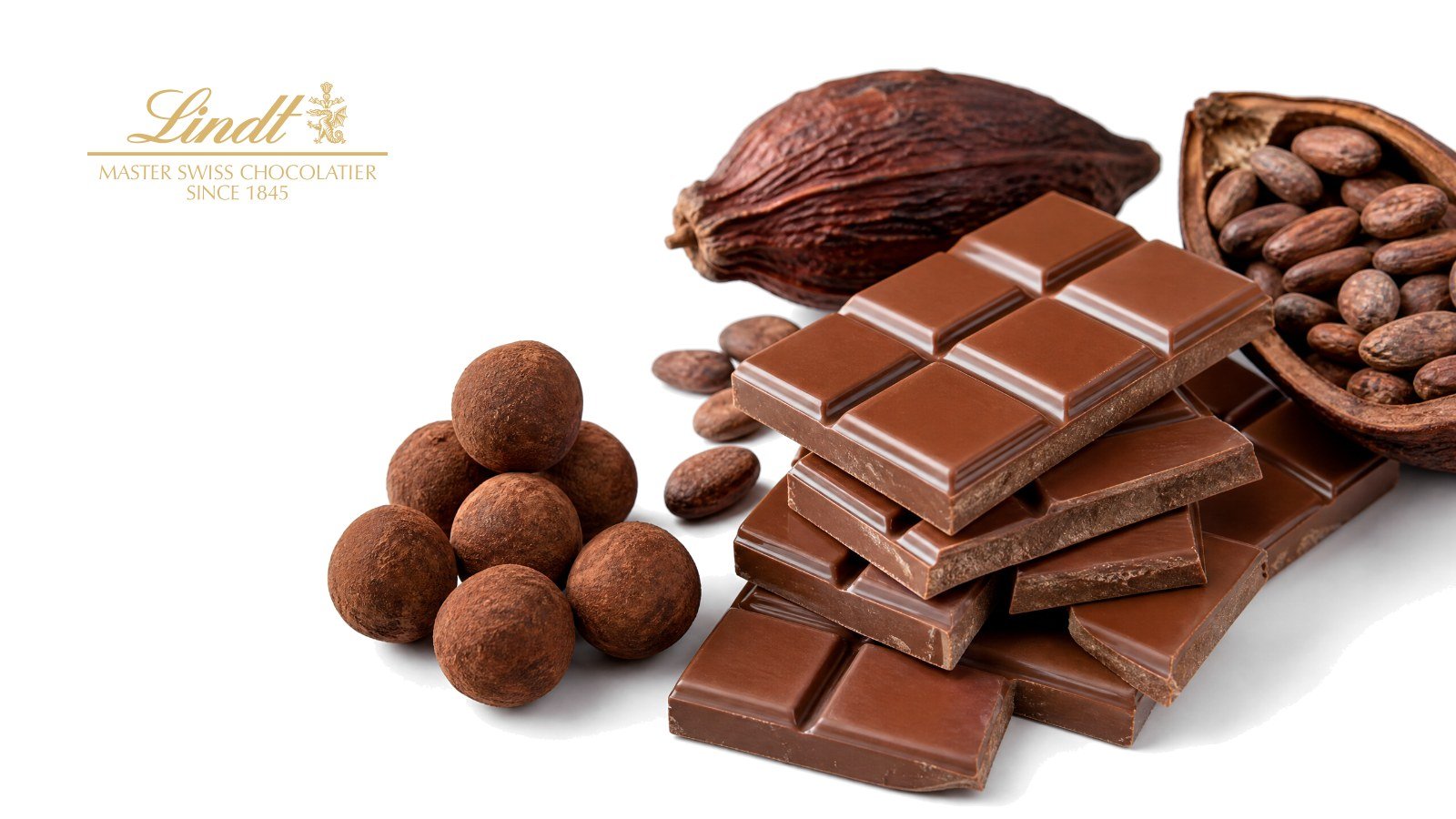 A broken bar of milk chocolate, chocolate truffles and cocoa pods on white, with the Lindt logo
