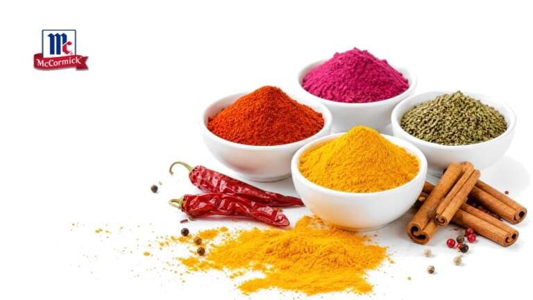 Bowls of paprika, turmeric, beet powder and herbs with dried chilies and cinnamon on white, with the McCormick logo